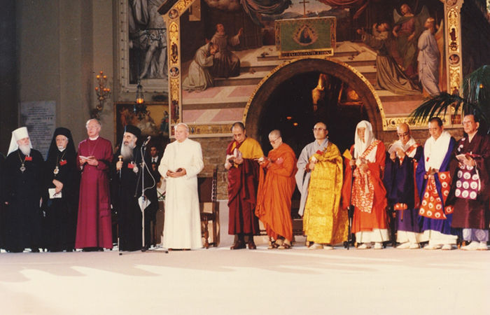 Juan Pablo II presidiendo el primer encuentro de Asís en 1986. Se encuentra dentro de la Basílica de Santa María de los Ángeles, rodeado de los representantes de las "religiones" Juan Pablo II presidiendo el primer encuentro de Asís en 1986. Se encuentra dentro de la Basílica de Santa María de los Ángeles, rodeado de los representantes de las "religiones"
